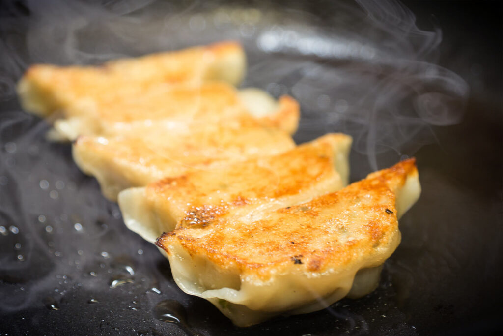 Gyoza sizzling on the hot plate while cooking