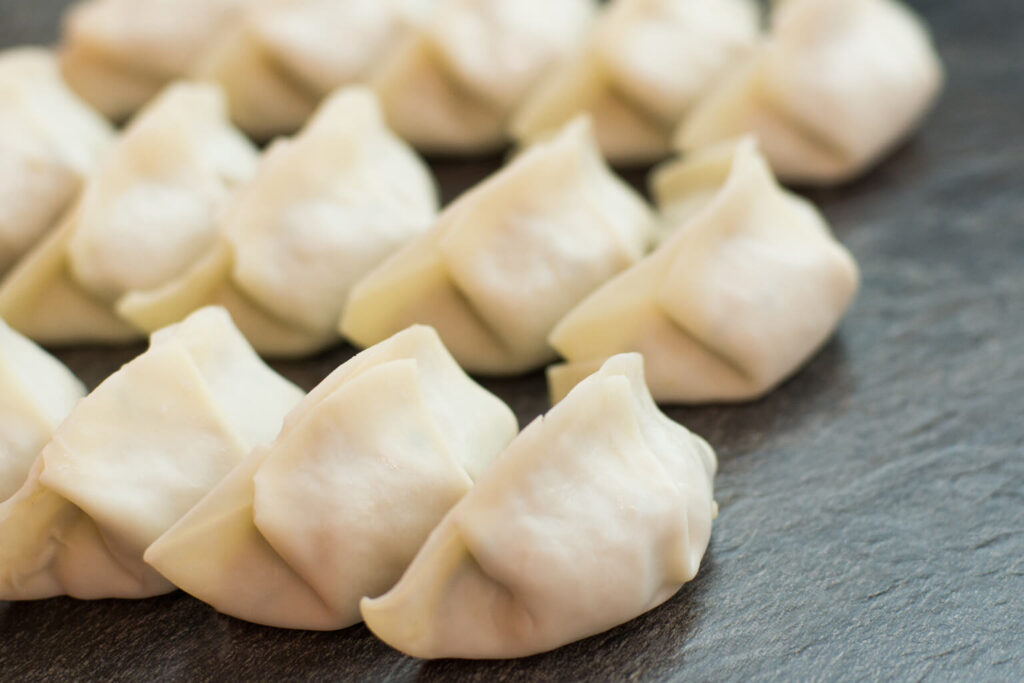 Uncooked gyoza dumplings lined up and ready to cook