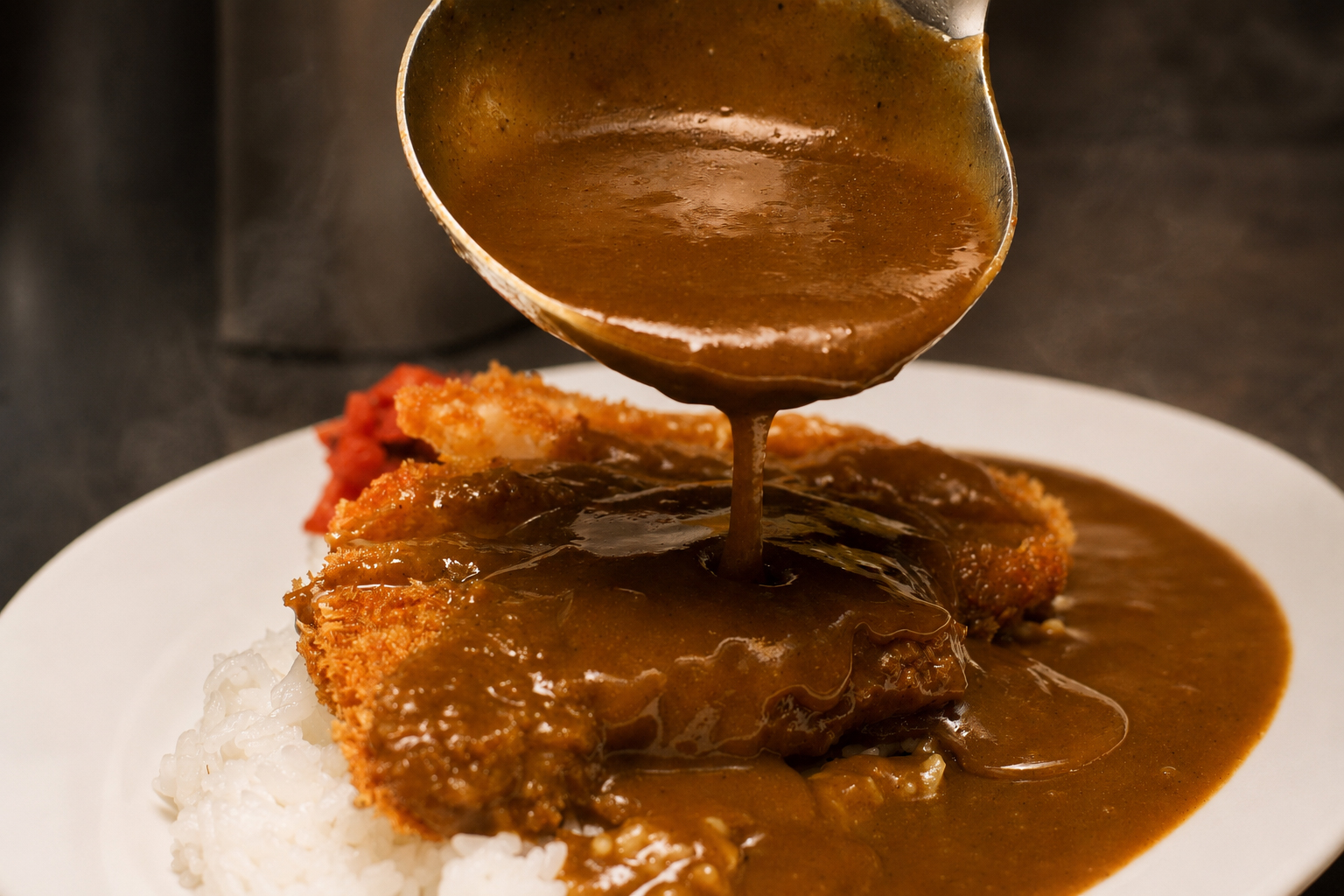 House-made Japanese curry being poured over freshly fried katsu